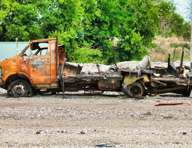 a rusted out truck sitting on top of a dirt field