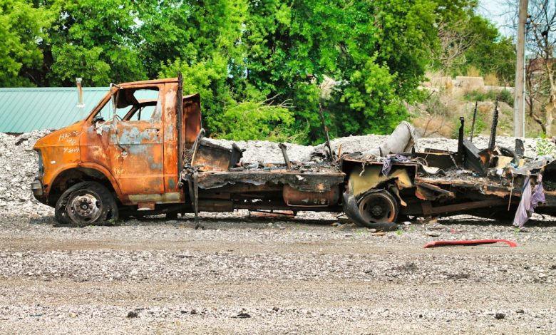 a rusted out truck sitting on top of a dirt field