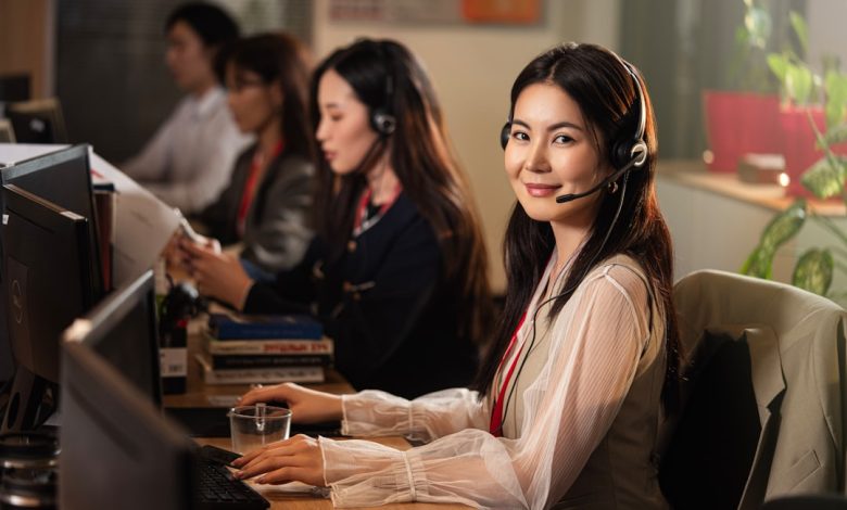 A smiling woman wearing a headset at a computer.