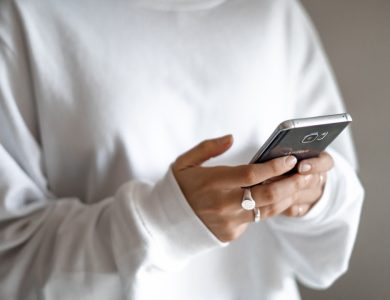 person in white long sleeve shirt holding black smartphone