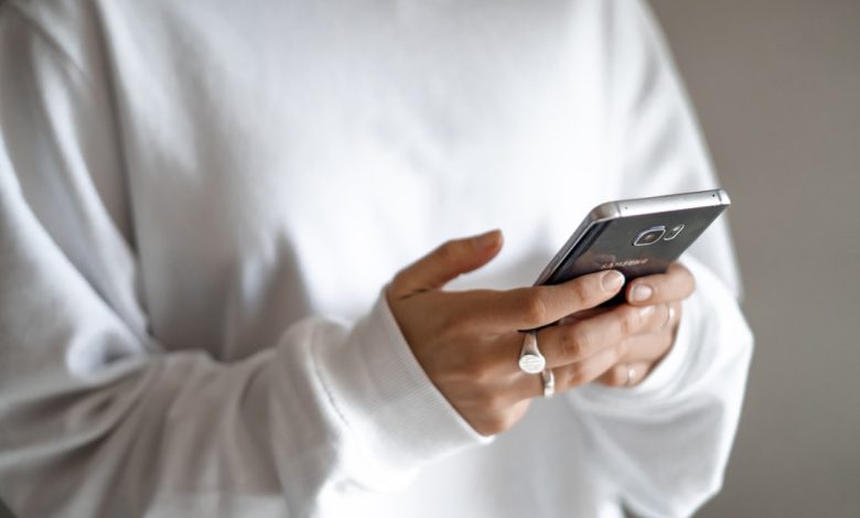 person in white long sleeve shirt holding black smartphone