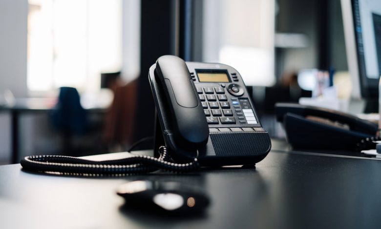 black ip desk phone on black wooden table