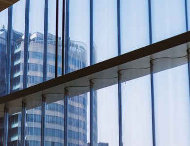 Reflection of a modern office building captured through a glass window indoors.