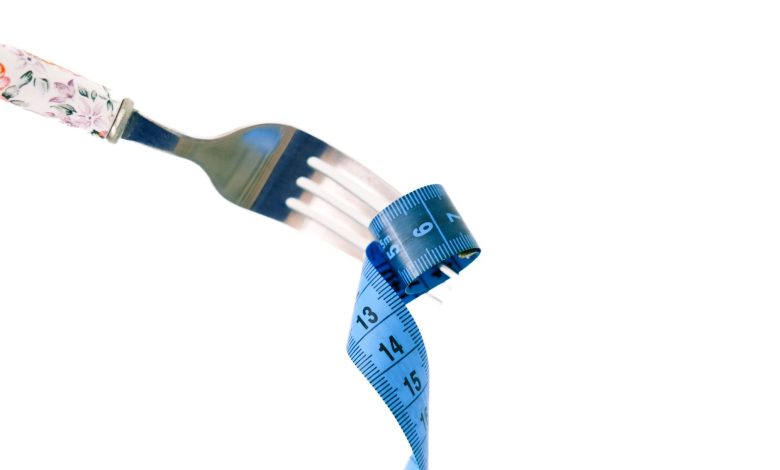 A fork twirls a blue measuring tape, symbolizing weight management and health.