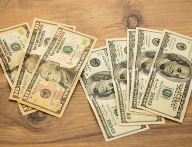 A collection of US dollar bills arranged on a wooden surface, showcasing currency denominations.