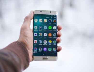Close-up of a hand holding a Samsung smartphone displaying various app icons, emphasizing technology and connectivity.