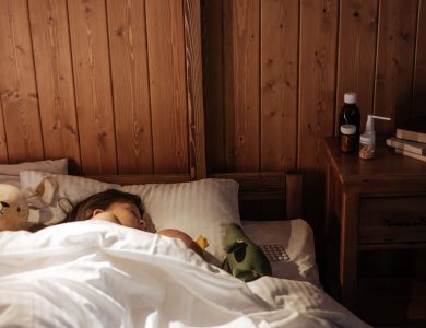 Child peacefully sleeping in a cozy wooden bedroom with toys and medicines by the bedside.