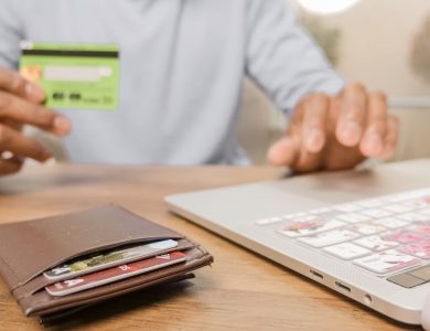 Close-up of hands with a bank card and laptop for online shopping. Perfect for illustrating e-commerce concepts.