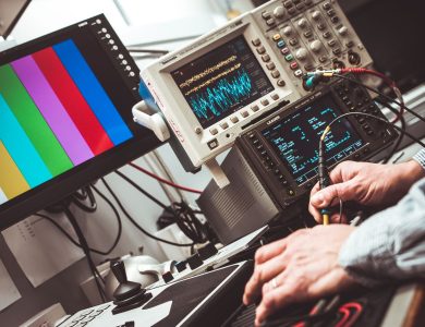 Technician operating laboratory electronic testing and measurement devices with colorful display.