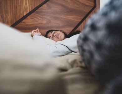A woman peacefully sleeping on a bed, conveying relaxation and comfort.