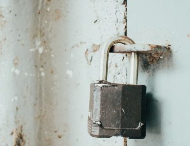 Detailed close-up of a rusty padlock securing a weathered door, highlighting age and texture.