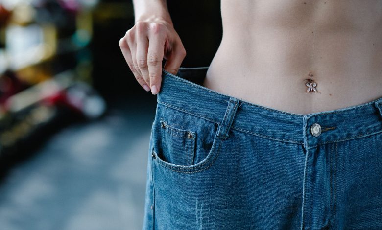 Close-up view of a slim waist and loose jeans representing weight loss or fitness progress.