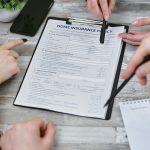 Three individuals collaborating on a home insurance policy document. Elements include a clipboard, notes, and pointing hands.