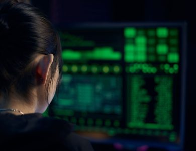 A woman focuses on data displayed on a computer screen in a dark room.