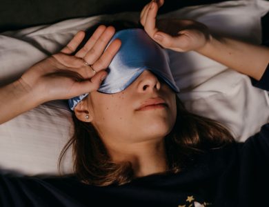 A woman peacefully resting with a sleep mask in a cozy indoor setting.