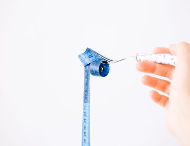 A blue measuring tape wrapped around a fork representing dieting or healthy eating concept.