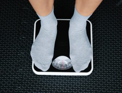Top view of feet in socks standing on a bathroom scale, indicating weight measurement.